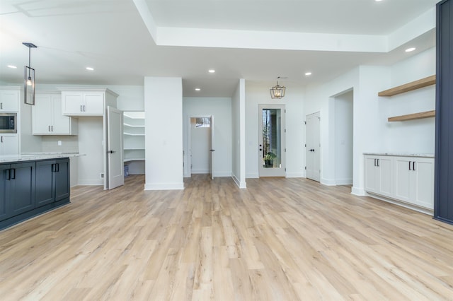 unfurnished living room with light wood finished floors, baseboards, a chandelier, and recessed lighting