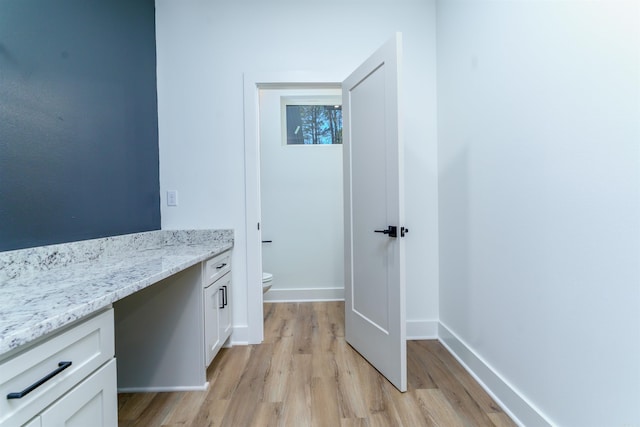 bathroom featuring wood finished floors, vanity, toilet, and baseboards