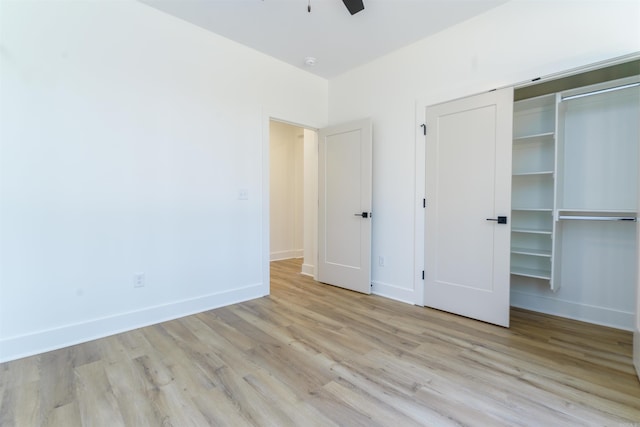 unfurnished bedroom with light wood-type flooring, a closet, and baseboards