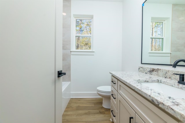 full bathroom featuring toilet, wood finished floors, vanity, and a healthy amount of sunlight