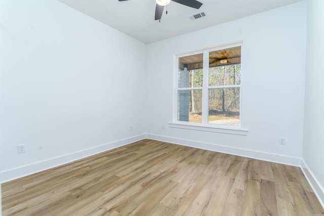 spare room with ceiling fan, light wood finished floors, visible vents, and baseboards