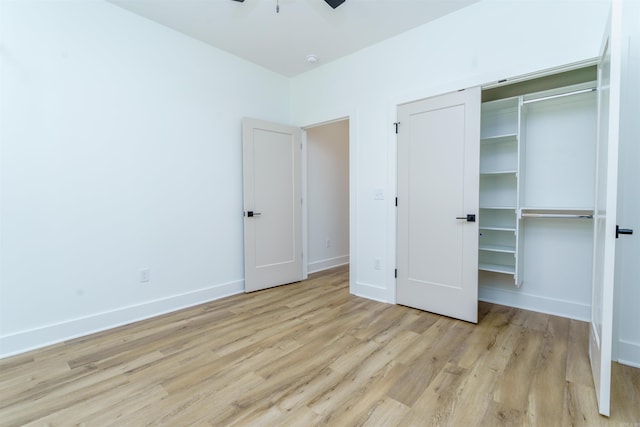 unfurnished bedroom featuring a ceiling fan, a closet, light wood-style flooring, and baseboards