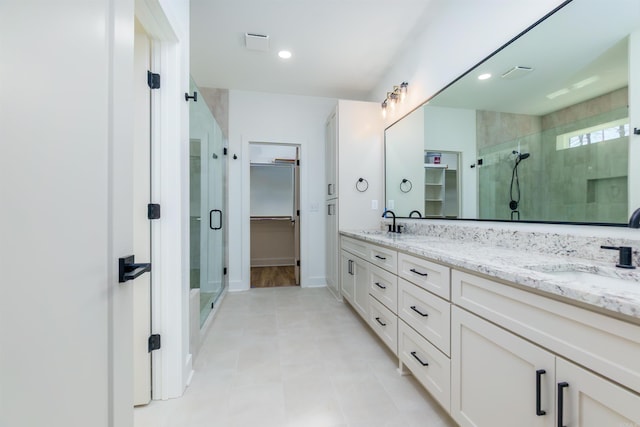 bathroom with a spacious closet, double vanity, a sink, and a shower stall