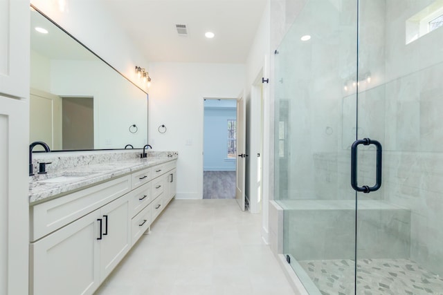 bathroom with double vanity, a shower stall, visible vents, and a sink