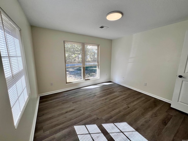 spare room featuring dark wood-type flooring and a textured ceiling