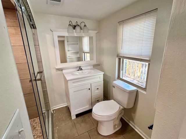 bathroom featuring toilet, vanity, tile patterned floors, and a shower with door