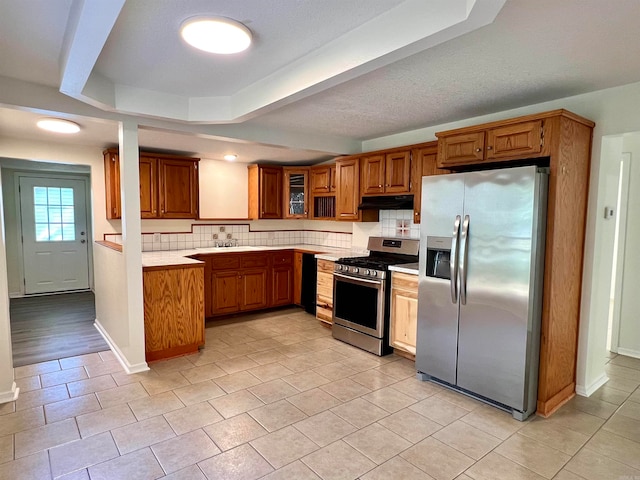 kitchen with appliances with stainless steel finishes, decorative backsplash, and a tray ceiling