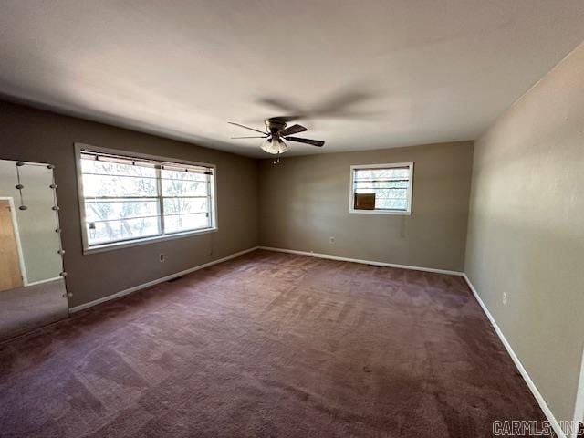 spare room featuring ceiling fan and dark colored carpet