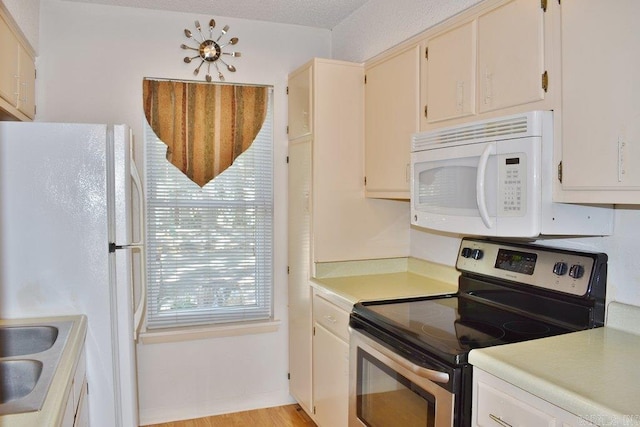 kitchen with white appliances, a textured ceiling, and light wood-type flooring