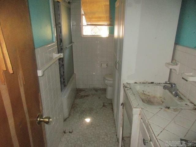 full bathroom featuring tile patterned floors, toilet, vanity, tile walls, and shower / bath combination with glass door