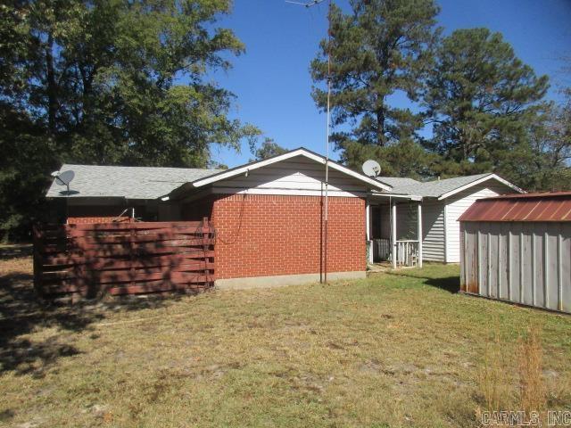 back of property featuring a storage unit and a lawn