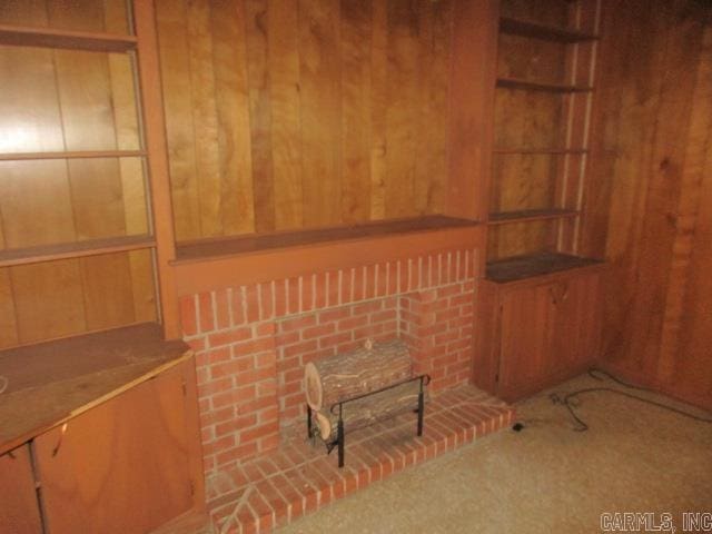 unfurnished living room featuring carpet flooring and wood walls