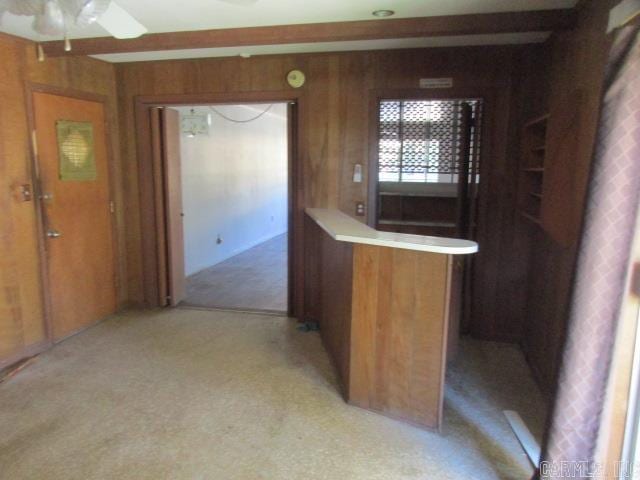 kitchen with ceiling fan, light carpet, and wood walls