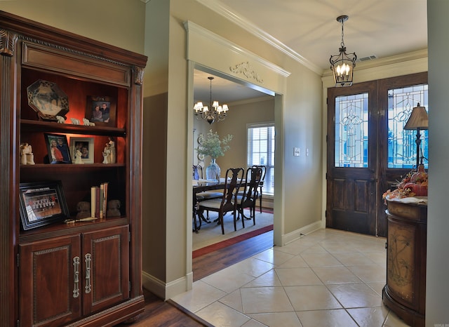 entrance foyer with light hardwood / wood-style floors, crown molding, french doors, and an inviting chandelier