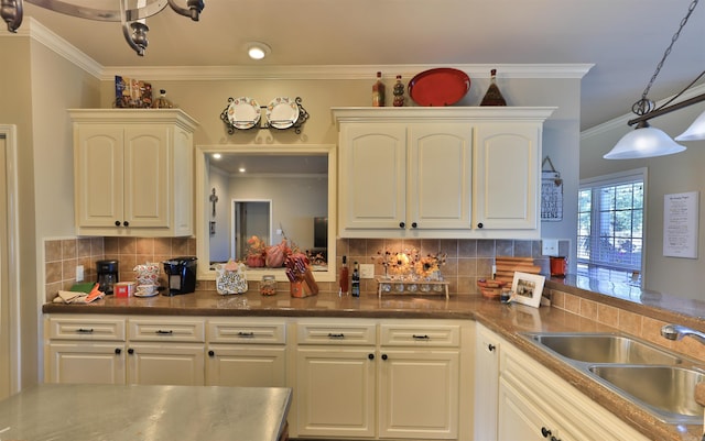 kitchen with white cabinets, backsplash, ornamental molding, pendant lighting, and sink