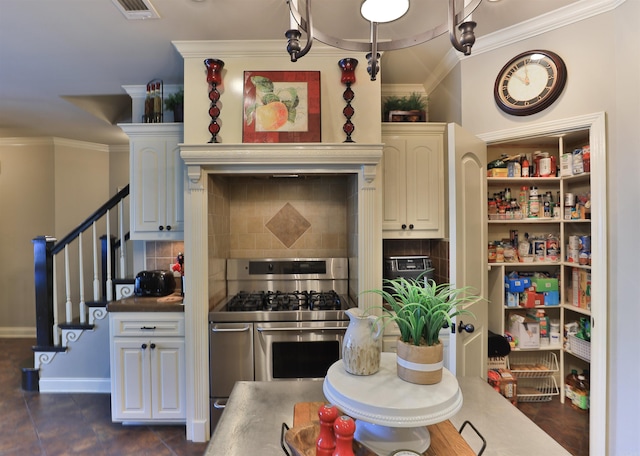 kitchen featuring stainless steel gas stove, crown molding, backsplash, and dark tile patterned flooring