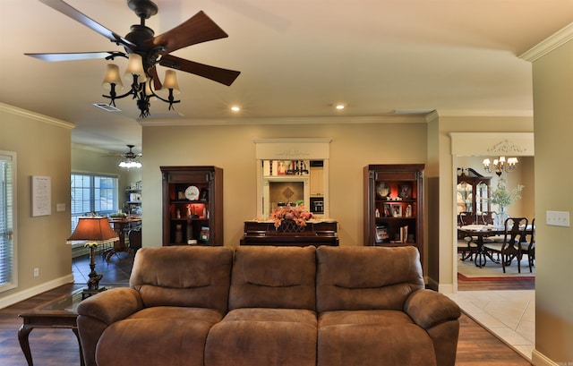 living room with crown molding, hardwood / wood-style floors, and ceiling fan with notable chandelier