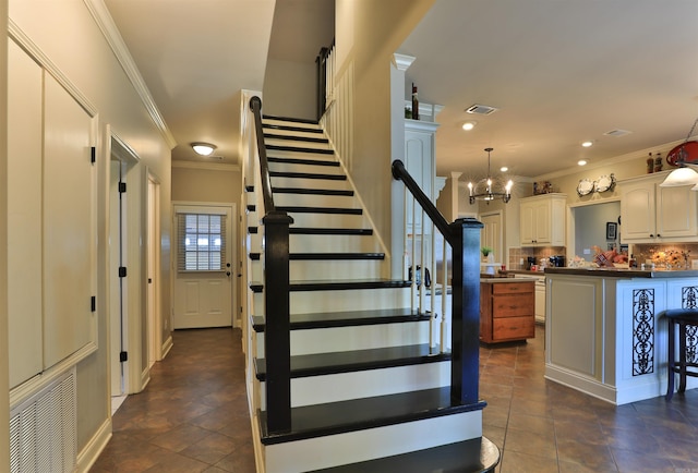 stairs with tile patterned floors, crown molding, and an inviting chandelier