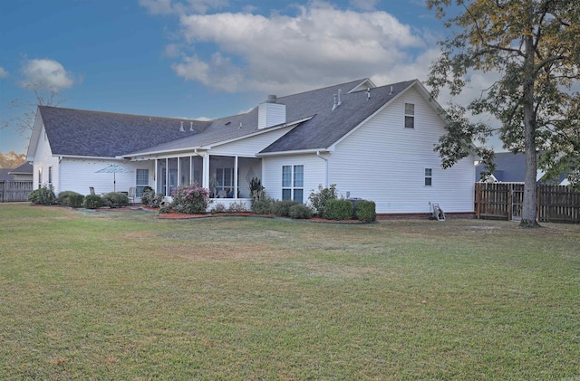 rear view of property featuring a sunroom, a yard, a chimney, and fence