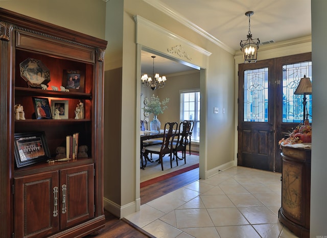 entrance foyer featuring an inviting chandelier, ornamental molding, and baseboards
