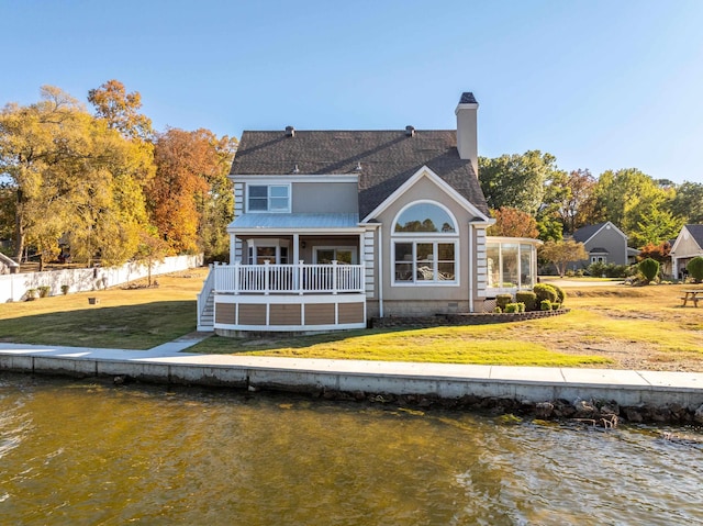 rear view of property with a water view and a lawn