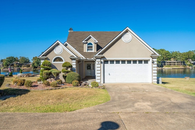 view of front of property featuring a garage, a front lawn, and a water view