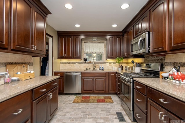 kitchen with sink, dark brown cabinetry, stainless steel appliances, and backsplash