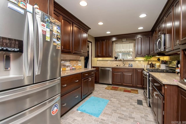 kitchen featuring dark brown cabinetry, tasteful backsplash, stainless steel appliances, and sink