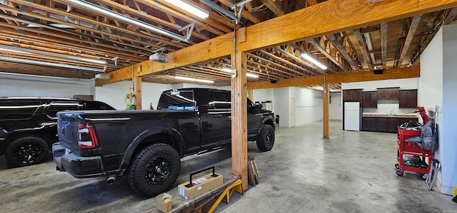 garage featuring sink, a garage door opener, and white refrigerator