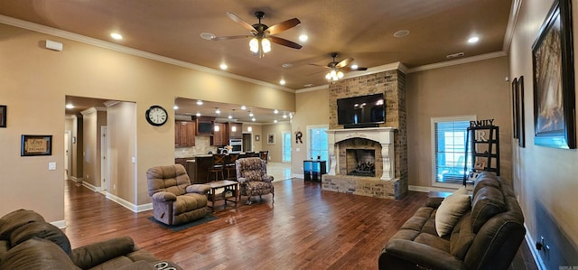 living room featuring ceiling fan, ornamental molding, dark hardwood / wood-style floors, a high ceiling, and a fireplace