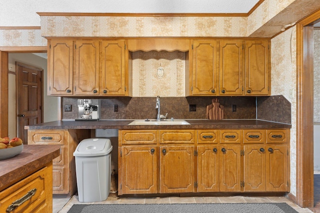 kitchen featuring ornamental molding, sink, decorative backsplash, and a textured ceiling