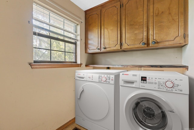 clothes washing area with cabinets and washer and clothes dryer