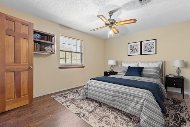 bedroom featuring dark wood-type flooring, ceiling fan, and a textured ceiling