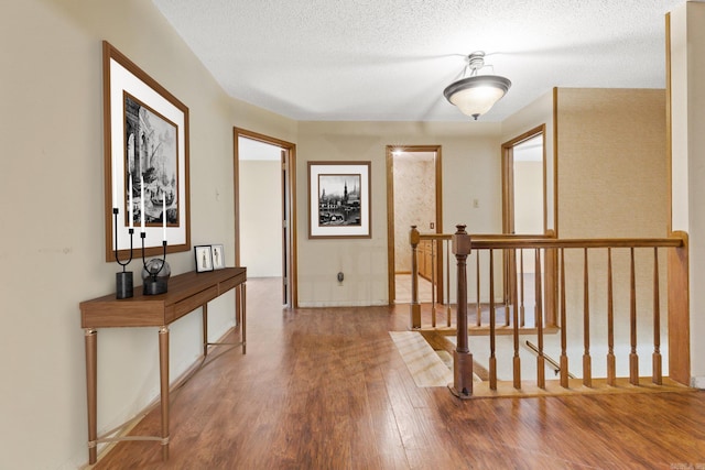 corridor with hardwood / wood-style floors and a textured ceiling