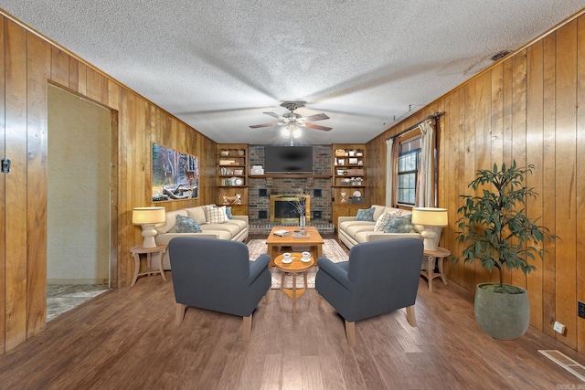 living room with hardwood / wood-style flooring, a textured ceiling, and wood walls