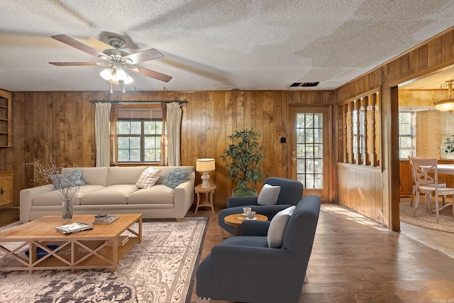 living room featuring wooden walls, wood-type flooring, and ceiling fan