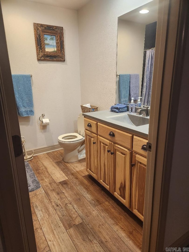 bathroom with toilet, hardwood / wood-style flooring, and vanity