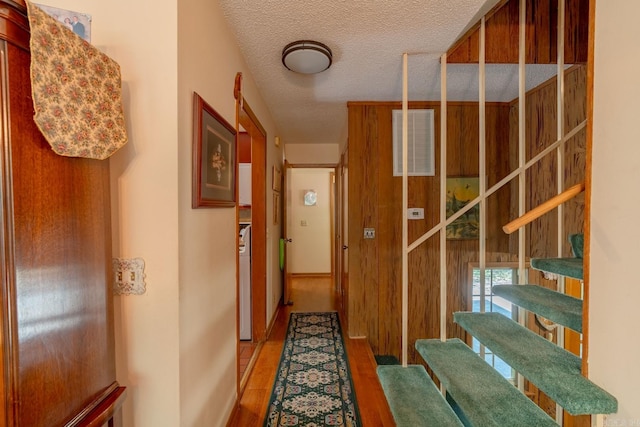 hall with wood-type flooring and a textured ceiling