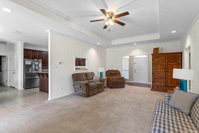 living room with light carpet, crown molding, a tray ceiling, and ceiling fan