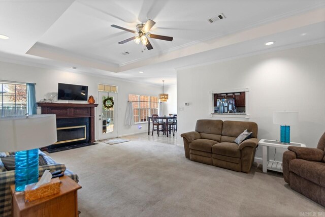 carpeted living room featuring crown molding, a raised ceiling, and ceiling fan