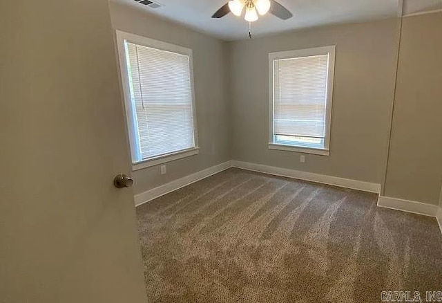 empty room featuring ceiling fan and dark carpet