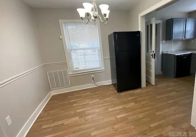 unfurnished dining area featuring light hardwood / wood-style floors and a chandelier