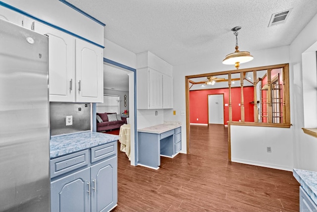 kitchen with ceiling fan, pendant lighting, white cabinets, stainless steel refrigerator, and dark hardwood / wood-style flooring