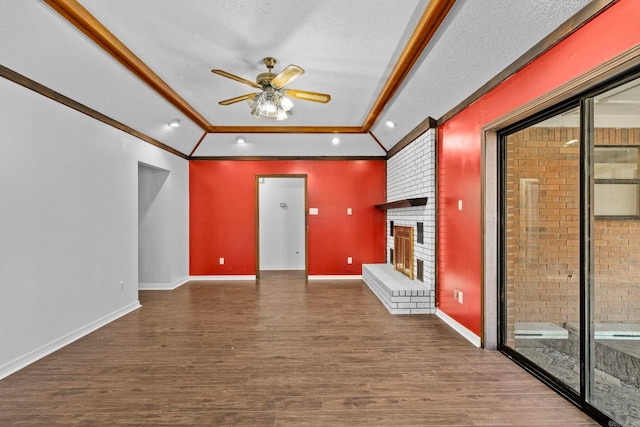 unfurnished living room featuring dark hardwood / wood-style floors, vaulted ceiling, a brick fireplace, a textured ceiling, and ceiling fan