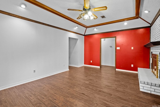 unfurnished living room featuring ornamental molding, dark hardwood / wood-style floors, a textured ceiling, and a brick fireplace