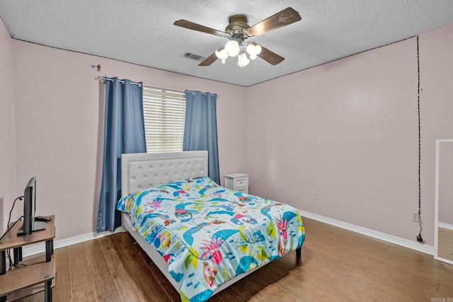 bedroom with a textured ceiling, hardwood / wood-style flooring, and ceiling fan