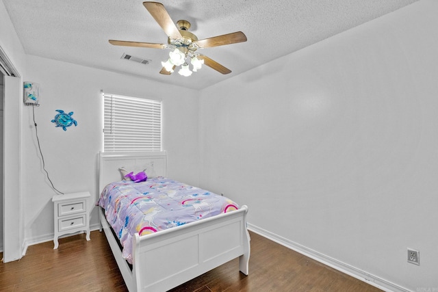 bedroom with a textured ceiling, dark wood-type flooring, and ceiling fan