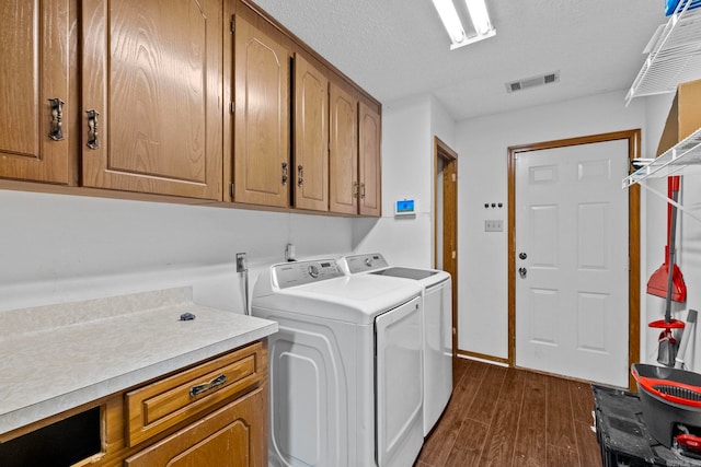 laundry area with independent washer and dryer, a textured ceiling, cabinets, and dark hardwood / wood-style flooring