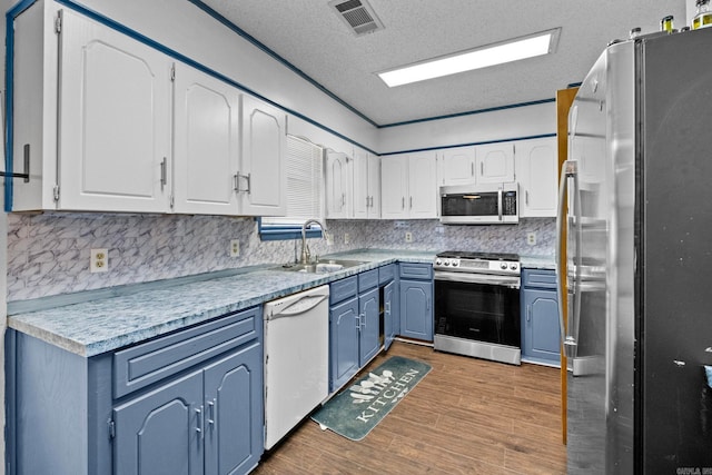 kitchen with sink, appliances with stainless steel finishes, dark wood-type flooring, and white cabinetry