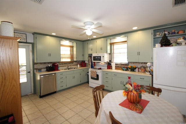 kitchen featuring white appliances, sink, green cabinetry, backsplash, and ceiling fan